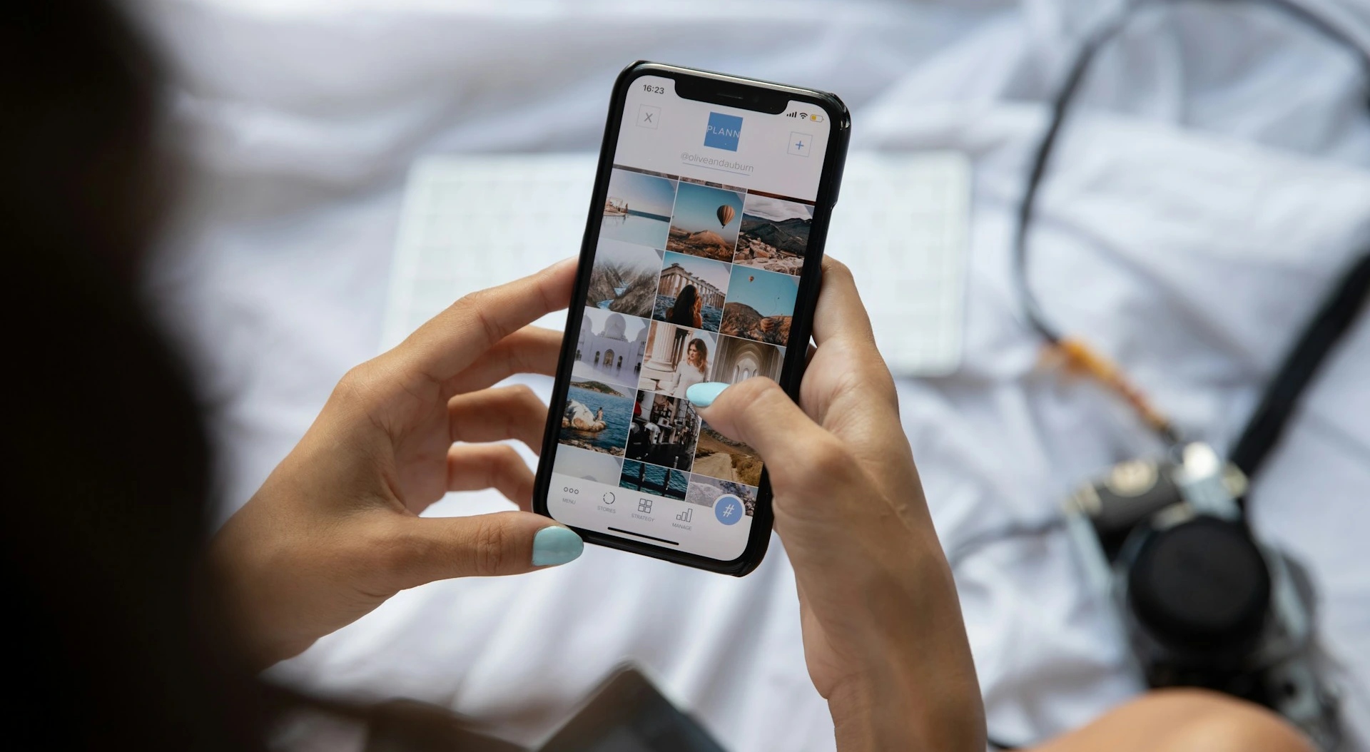 A person's hands hold a smartphone displaying a grid of travel photos.