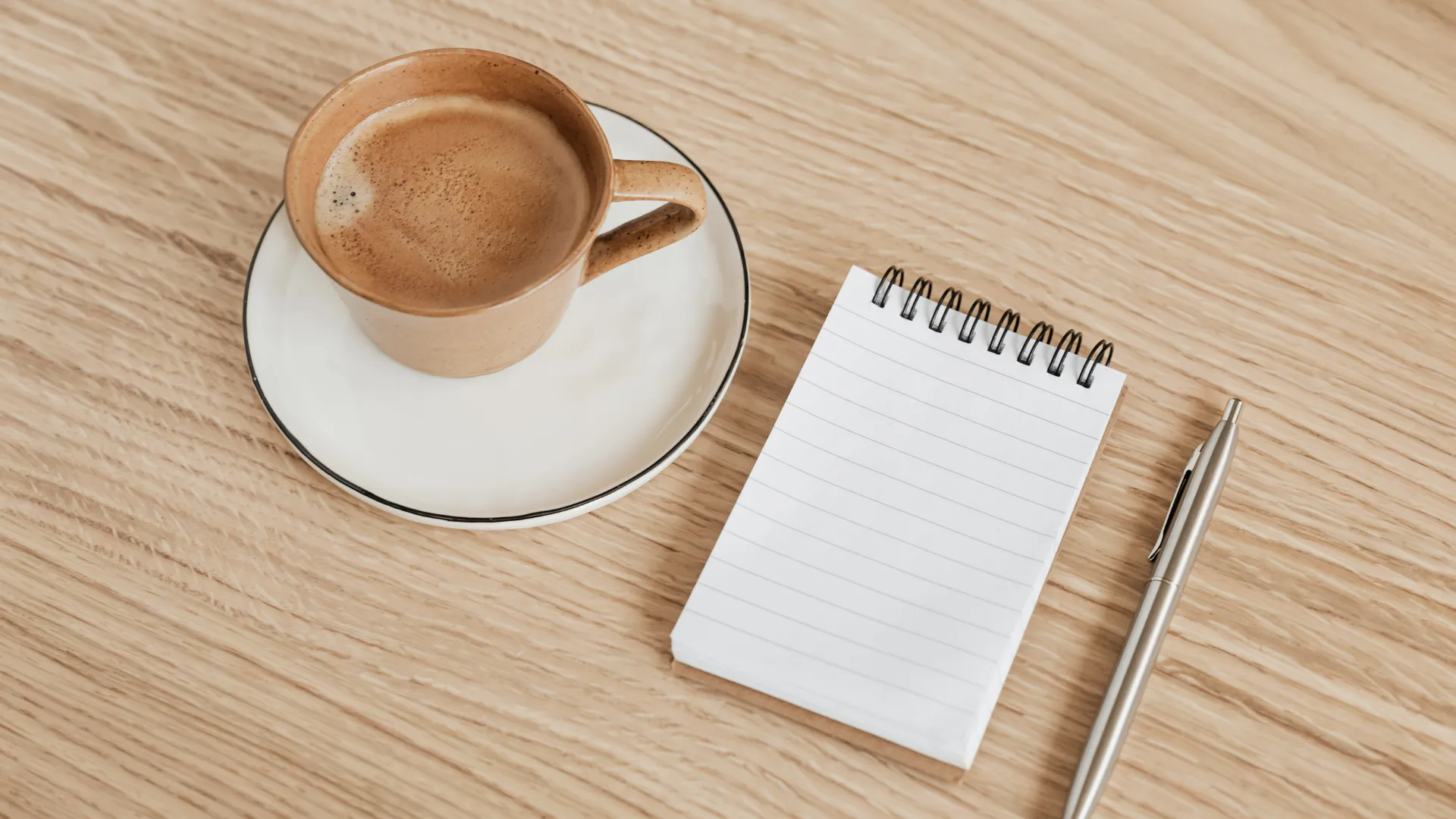 A note book, a pen and cup of coffee on a table ready to start learning about "What Is Affiliate Marketing"