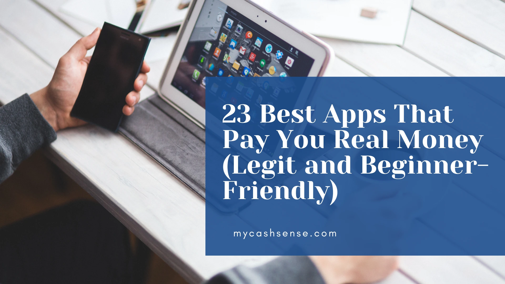 Close-up of hands holding a smartphone over a tablet displaying app icons, overlaid with a blue banner promoting "23 Best Apps That Pay You Real Money (Legit and Beginner-Friendly)" from mycashsense.com.
