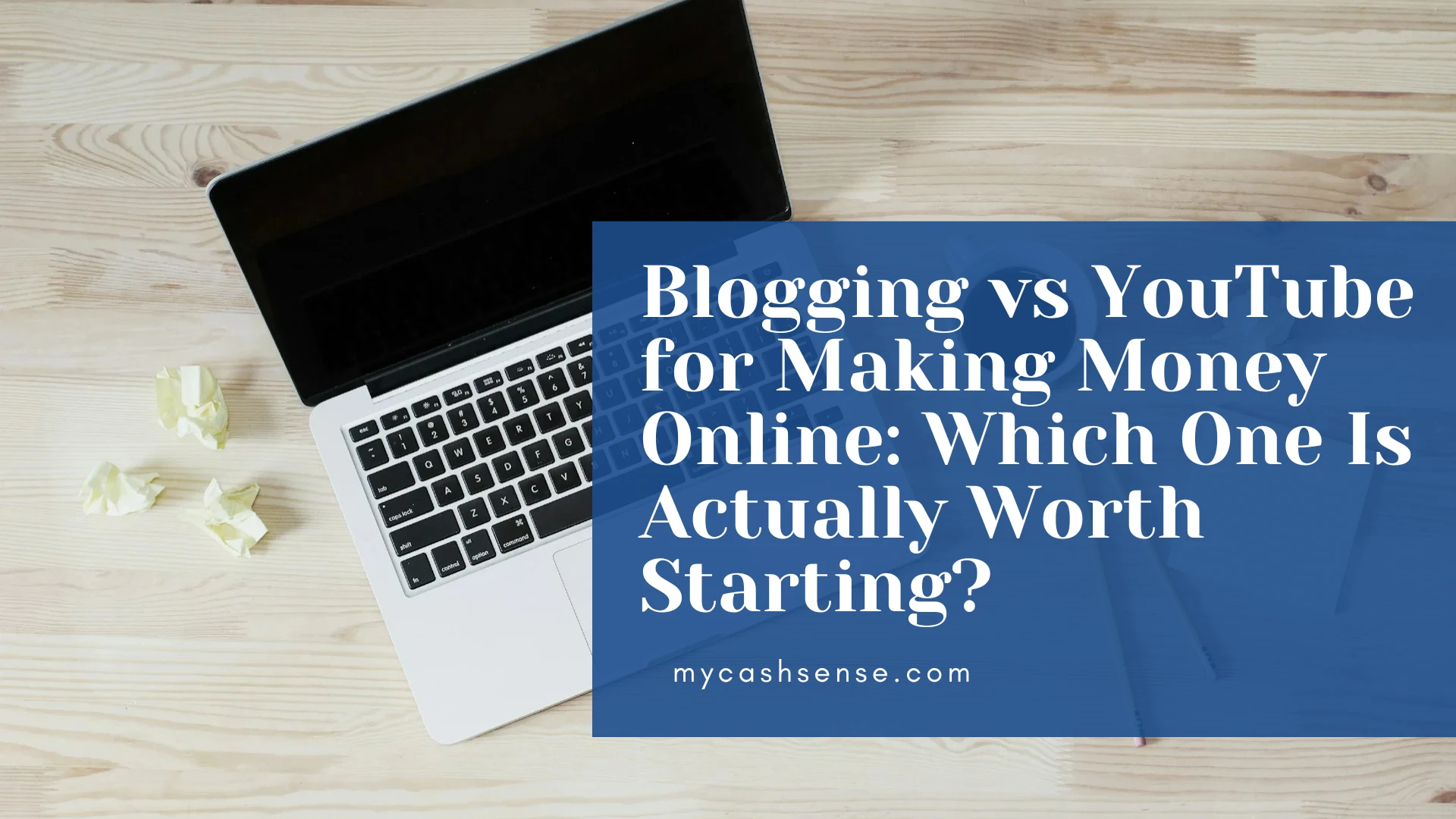 Overhead view of a laptop on a light wood desk next to crumpled paper, overlaid with a blue banner asking "Blogging vs YouTube for Making Money Online: Which One Is Actually Worth Starting?".