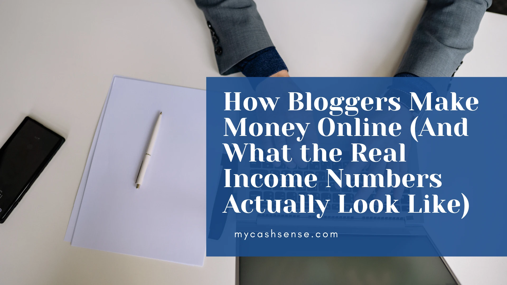 Overhead view of a desk with papers, a phone, and a blue graphic overlay reading "How Bloggers Make Money Online (And What the Real Income Numbers Actually Look Like) mycashsense.com".