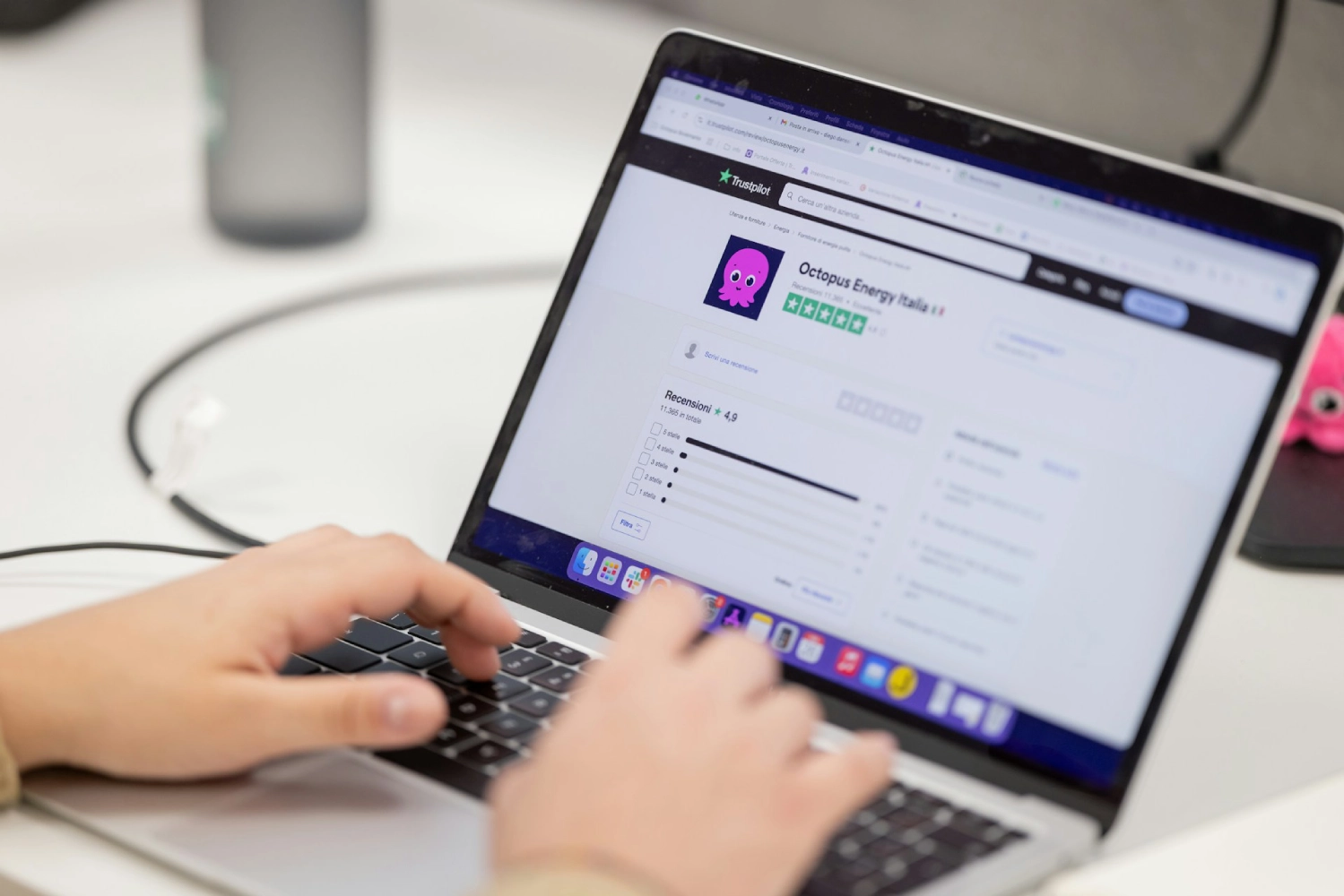 Hands typing on a laptop displaying the Octopus Energy Italia Trustpilot review page with a 4.5 rating.