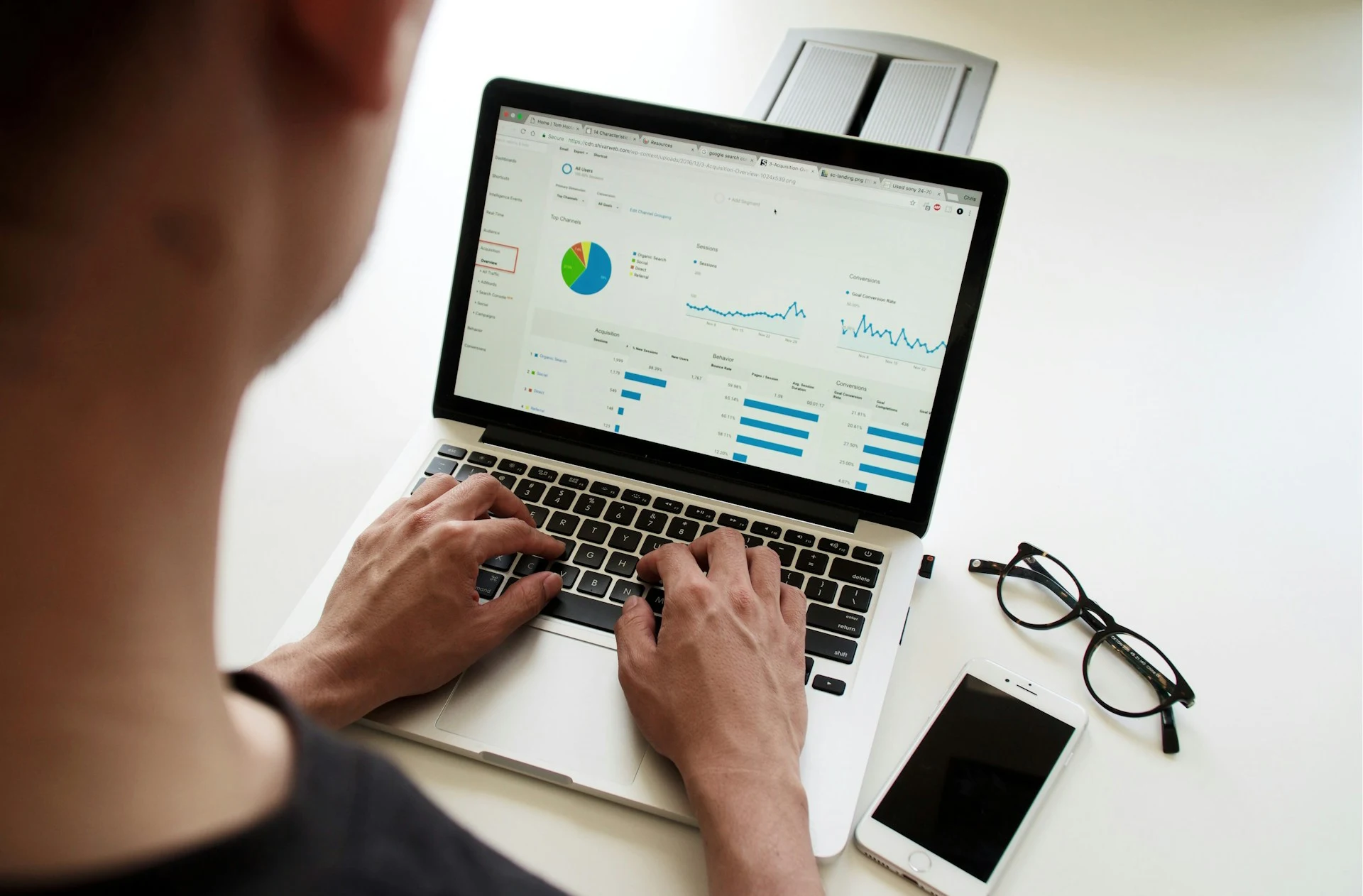 Person's hands typing on a laptop displaying a business analytics dashboard with charts and graphs.