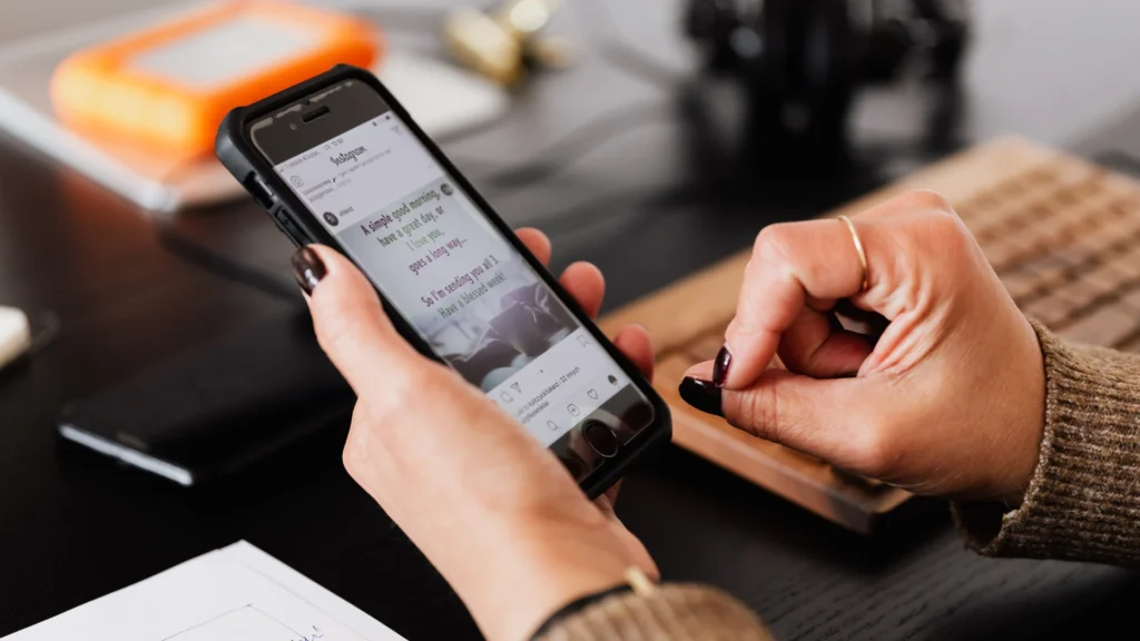 Person holding a smartphone displaying an Instagram post with a "good morning" message and an image.