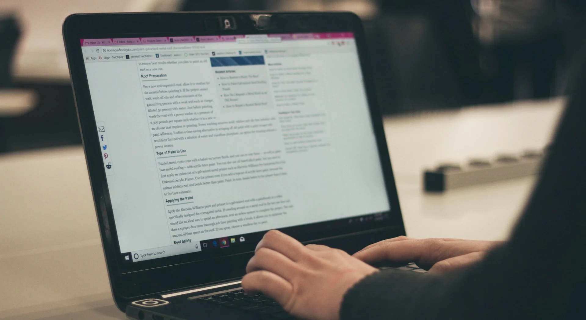 Person using a laptop to read an online article about paint types and application techniques.