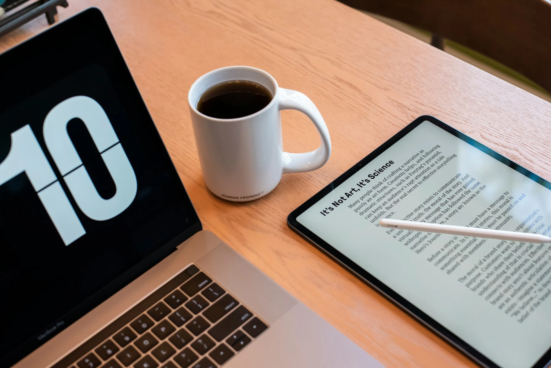 Laptop, coffee mug, and tablet displaying an article titled “It’s Not AI, It’s Science” arranged on a wooden desk.