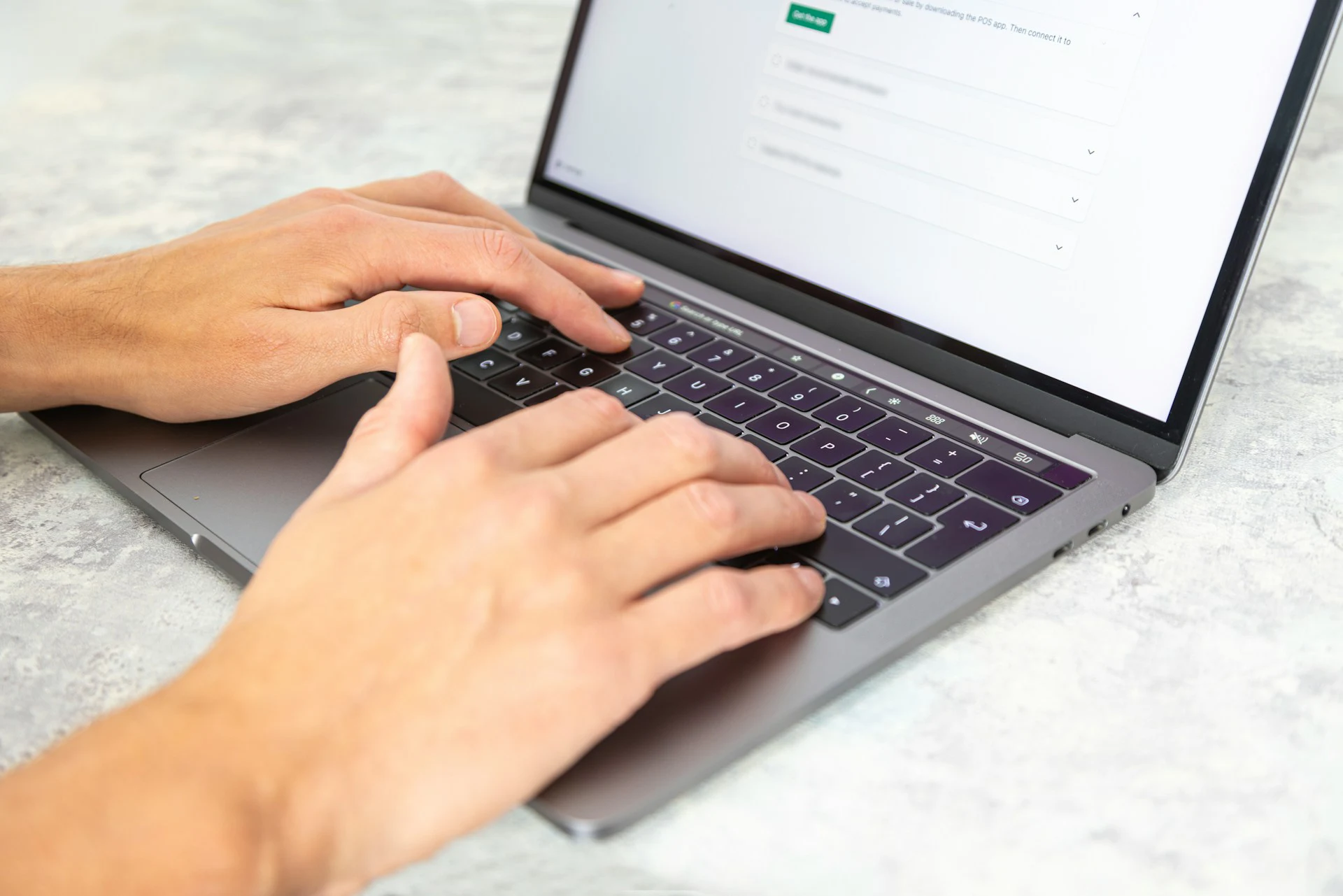 Hands type on a laptop keyboard, with a blurred online form open on the screen.